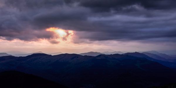Sun covered by dark clouds over the mountains