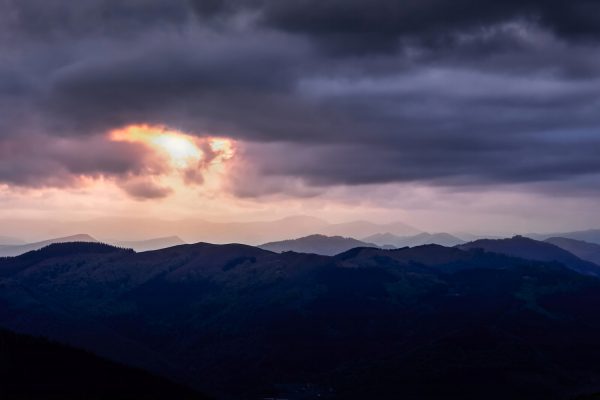 Sun covered by dark clouds over the mountains